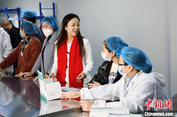 “雨衣妹妹”刘仙在口罩厂与工人们在一起。　张浪 摄
